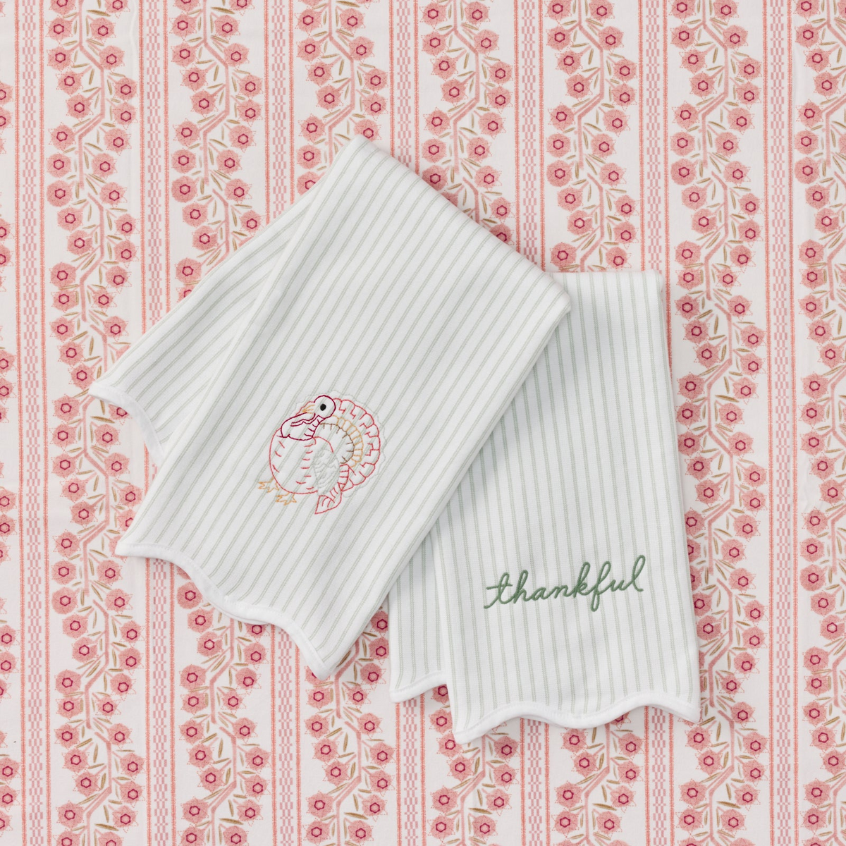 Two green striped kitchen towels with scalloped edges, featuring an embroidered turkey and the word thankful.